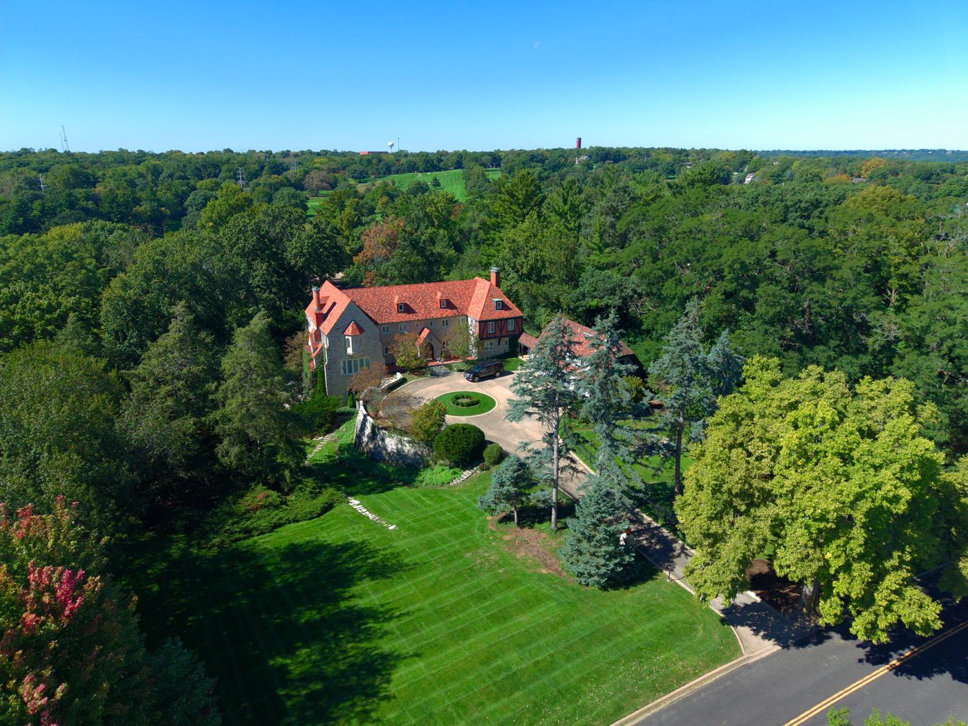 Aerial view of a red-tile-roof Tudor estate with striped lawn and circular drive in Peoria, Illinois