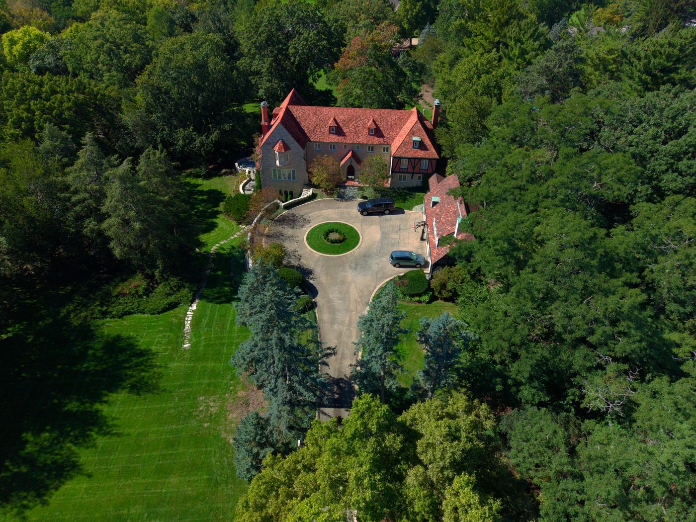 Top-down aerial of an estate roofline, circular drive and manicured grounds